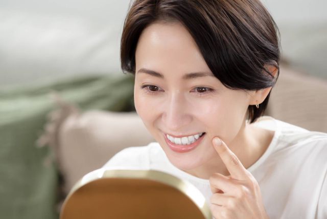 鏡で口元を見る女性